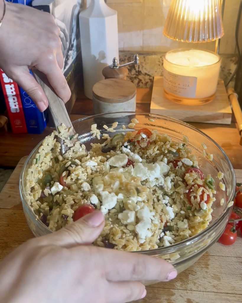Orzo salad being mixed together 